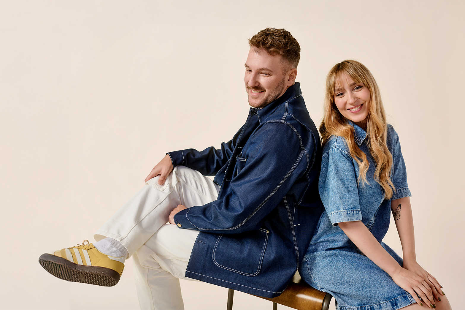 Ein Mann und eine Frau sitzen Rücken an Rücken und lachen.